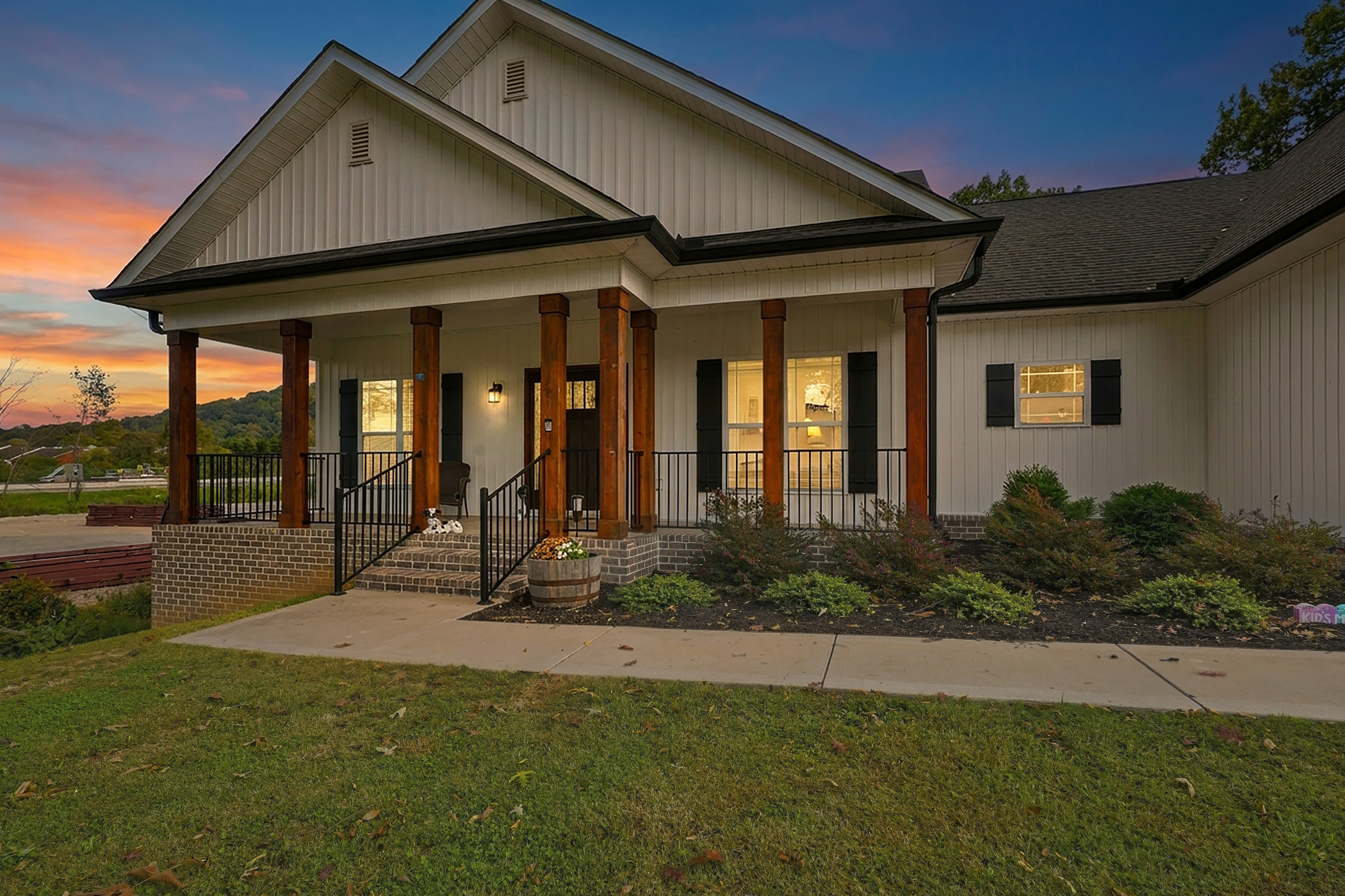 A white home with timber porch columns and glowing windows at dusk in Powell.